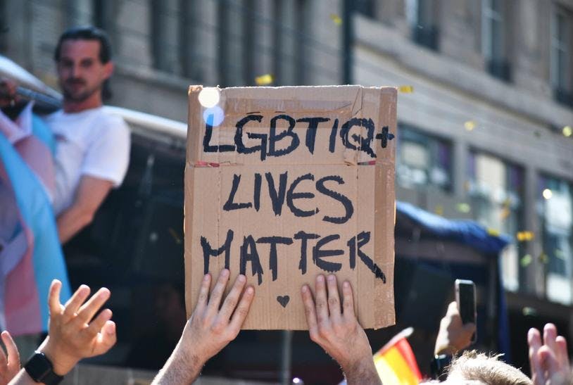 Deux mains tiennent une pancarte "LGBTIQ+ LIVES MATTER"