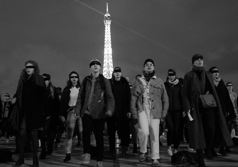 un groupe de personnes (femmes et minorités de genre) manifeste devant la Tour Eiffel les yeux bandés