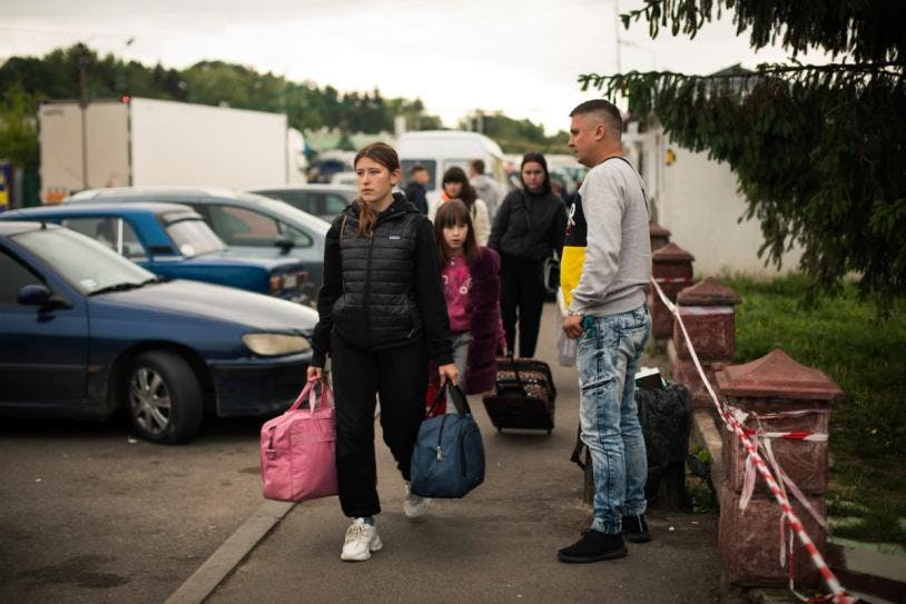 En Ukraine, plusieurs personnes avec des sacs rentrent chez elles, après avoir passé la frontière avec la Pologne.