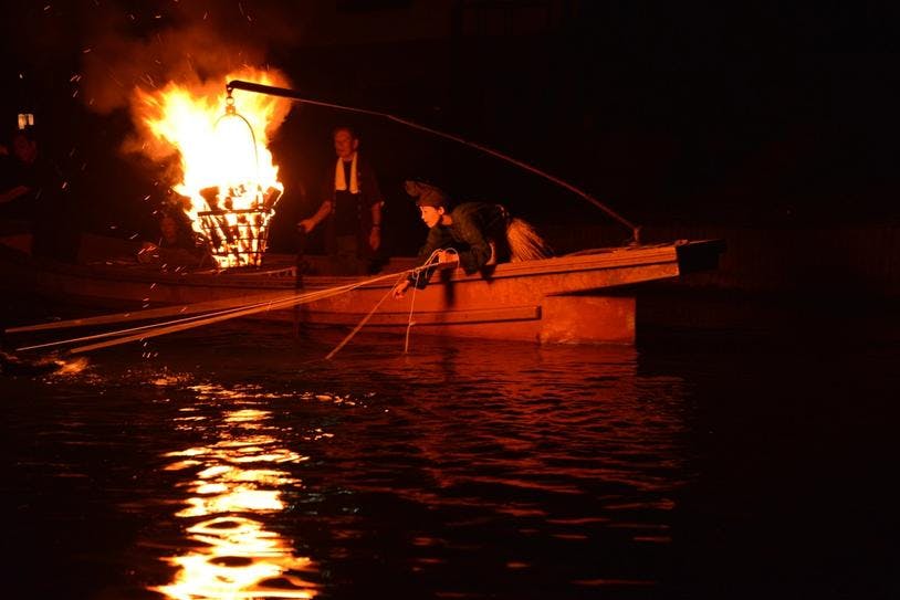 Sawaki Mariko sur un bateau avec des cormorans à la lumière d'un feu suspendu 