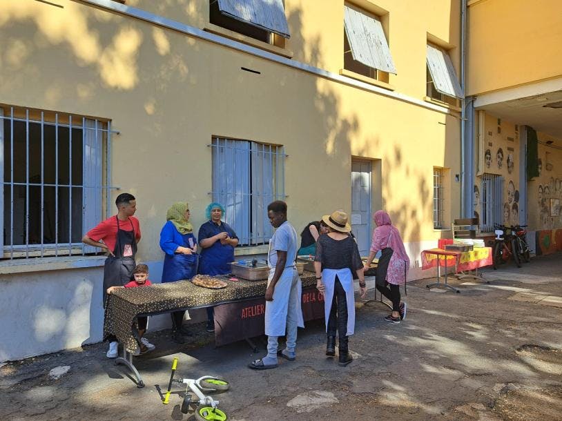 Dans la cour du CADA de La Cimade de Béziers, mise en place du repas du jour par l'équipe des cuisinières et cuisiniers.