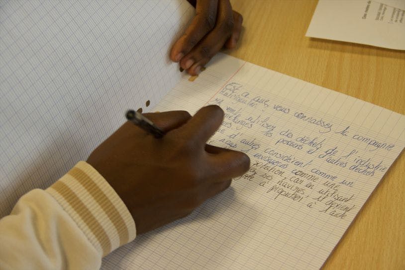 Un ou une élève écrit sur une feuille volante
