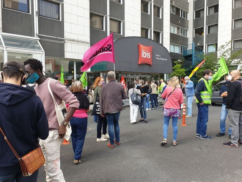 Des femmes et hommes, militants, journalistes ou soutiens de longue date sont debout devant l'hôtel Ibis des Batigolles